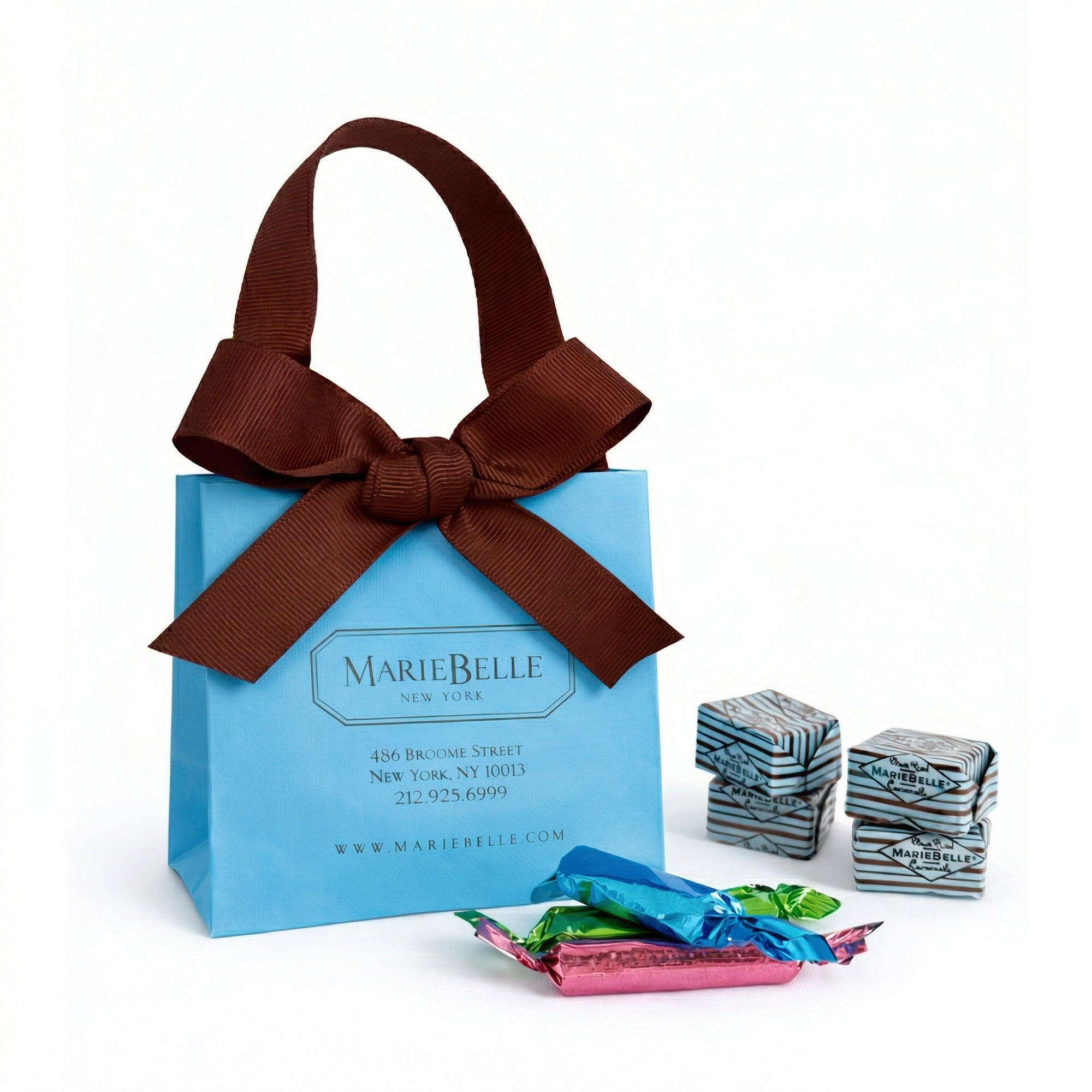Blue gift bag with brown ribbon and MarieBelle branding, surrounded by wrapped candies.