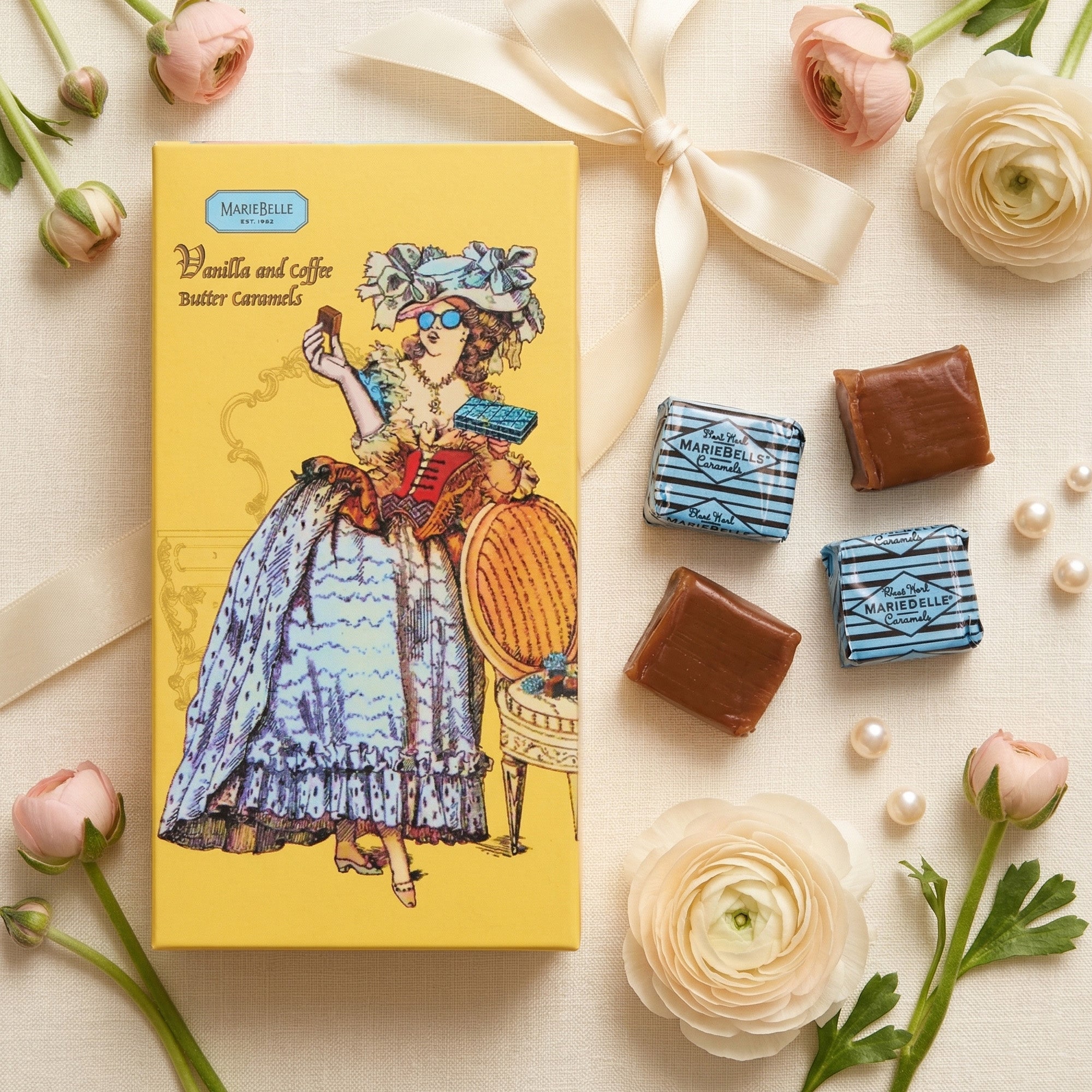 Chocolate box with illustrations of a woman and chocolates on a decorative surface with flowers and pearls.